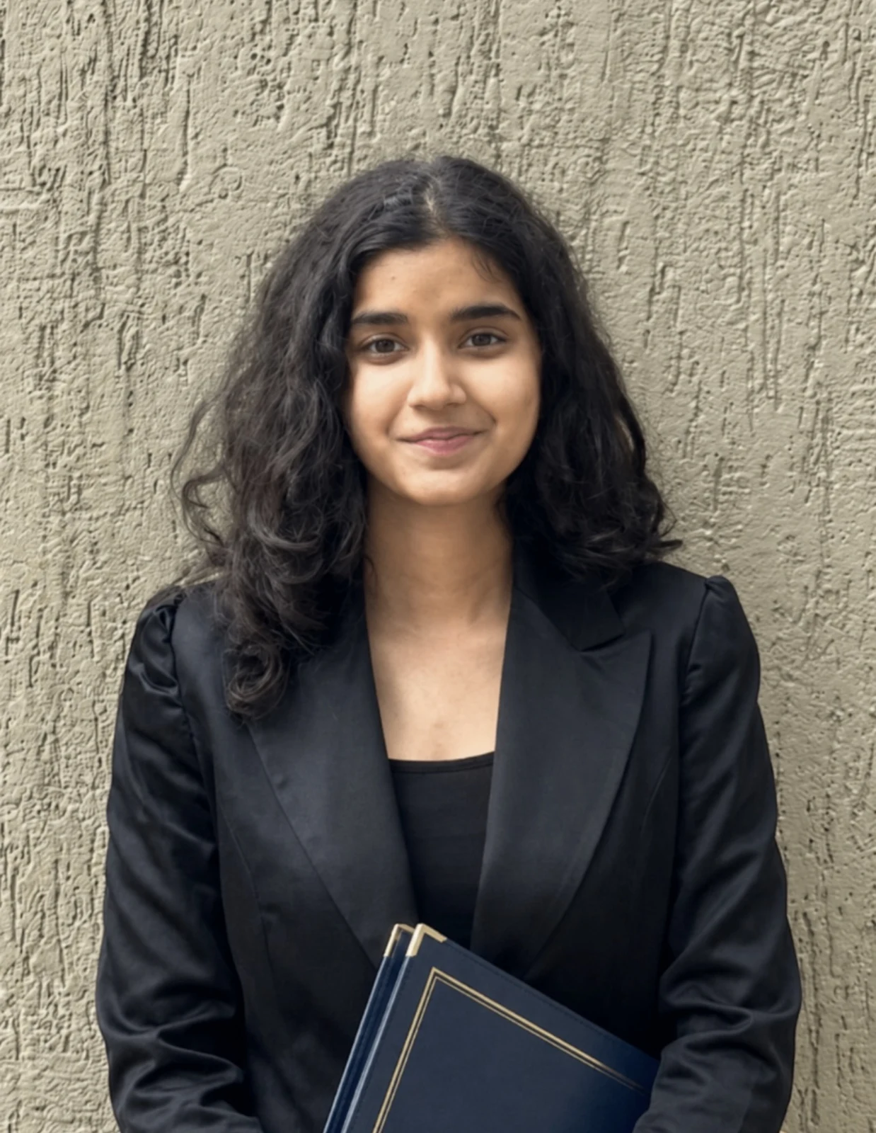 Ariana Agarwal, wearing a black blazer and holding a folder